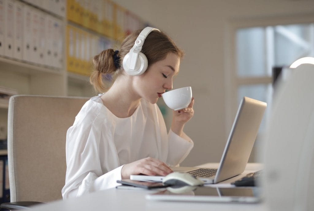 Femme qui boit une tasse de thé blanc en travaillant à l'ordinateur